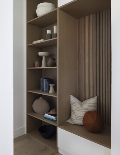 A room with a wooden shelf and a few pillows.