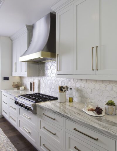 A kitchen with white cabinets and a marble counter top.