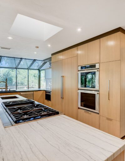 A modern kitchen with wooden cabinets and a large window.
